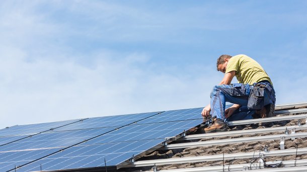 Installateur montiert ein Modul einer Photovoltaik-Anlage.