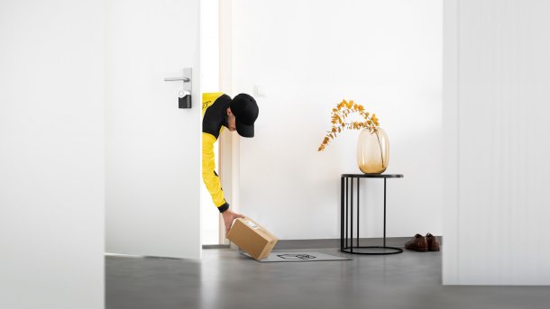 Paketbote legt Paket in Hausflur