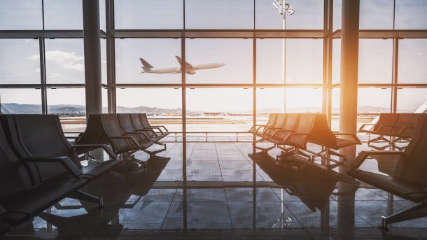 View from a waiting area at Barcelona Airport, with an airplane taking off in the background. 