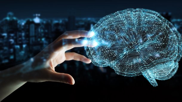 Eine Frauenhand greift nach einem im Raum schwebenden Gebilde aus leuchtenden Linien und Punkten, das ein menschliches Gehirn darstellt