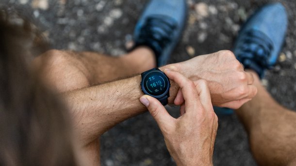Mann mit Sportschuhen prüft seine Smartwatch