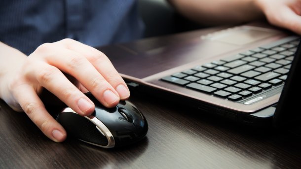Hand auf Maus, die andere auf einer Tastatur