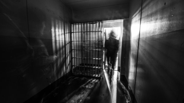 A blurred black and white shot of a person walking through a barred door