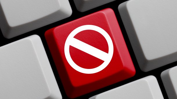 Ausschnitt einer Computertastatur mit grauen, leeren Tasten; nur eine Taste ist rot und zeigt ein Verbotsschild