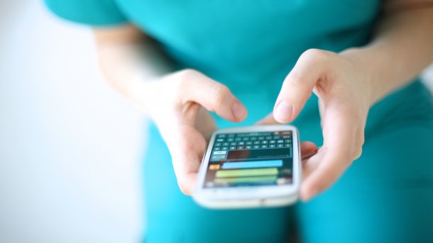 Frau im grünen Gewand schreibt eine Nachricht mit dem Smartphone