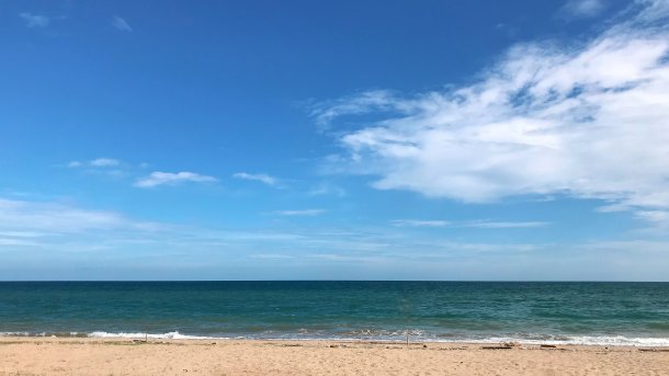 Strand mit blauem Himmel und von rechts ein paar Wolken