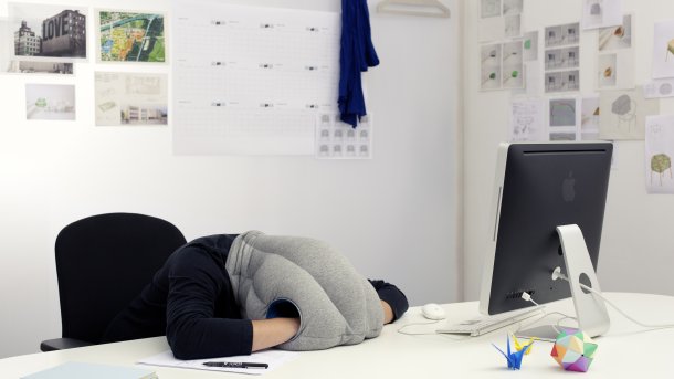 Frau stützt sich ermüdet auf Schreibtisch