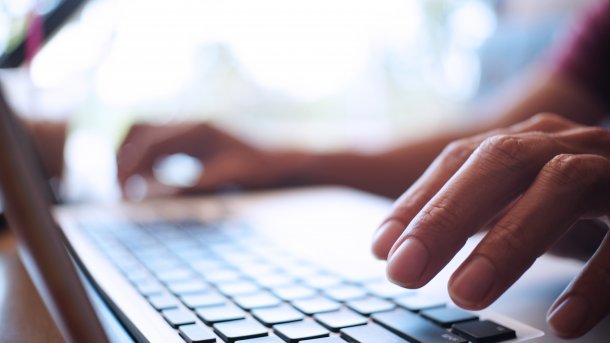 Tippende Hand auf Notebook-Tastatur.