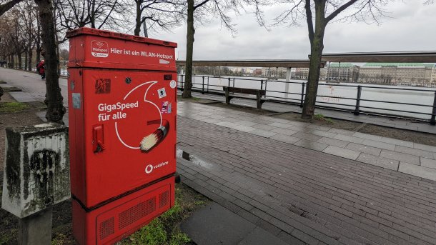 Ein Verteilerkasten mit Vodafone-Werbung, dahinter die Binnenalster