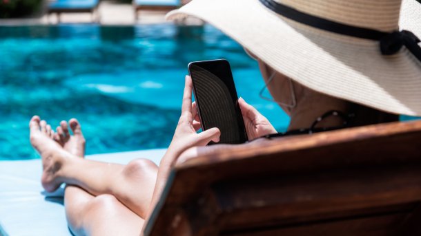Mutter sitzt im Freibad im Lehnstuhl und schaut auf ihr Smartphone. Wo ihre Kinder sich tummeln, ist ungewiss. Das finden Bademeister gefährlich.