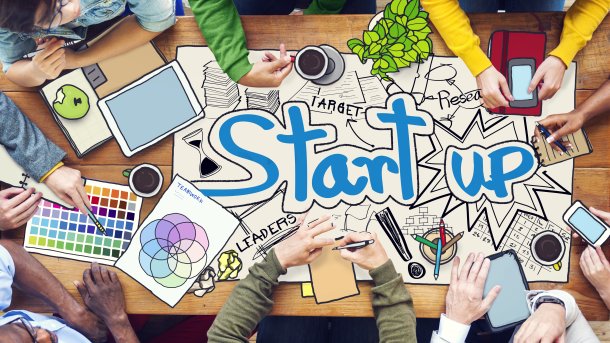 Symbolbild Startup, Personen sitzen um einen Tisch mit dem Wort Startup