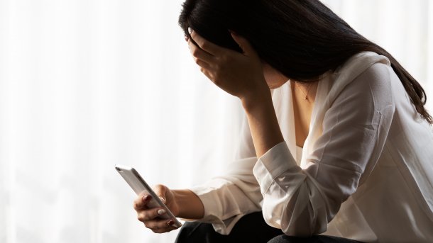 Frau am Smartphone, die sichtlich leidet