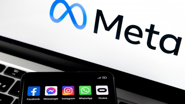 Meta-Logo auf einem Bildschirm, davor ein Anriss eines Smartphones mit Meta-Apps
