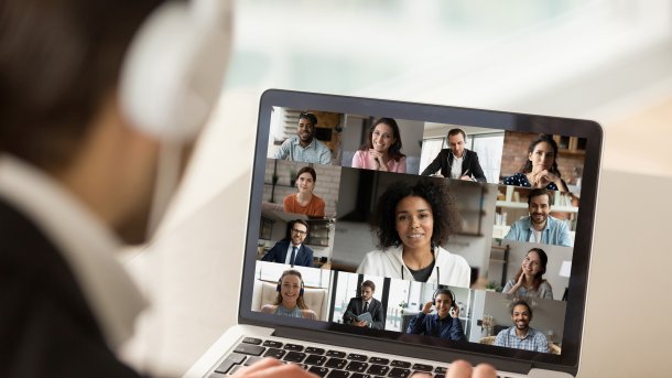 Man mit Kopfhörern vor Laptop mit Videokonferenz