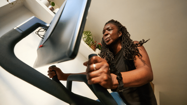 Schwarze Frau auf einem Zimmerfahrrad