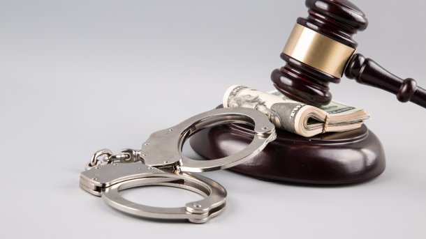 Judge's gavel, a bundle of dollar bills and handcuffs