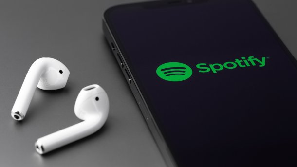Spotify logo on iPhone, with AirPods next to it