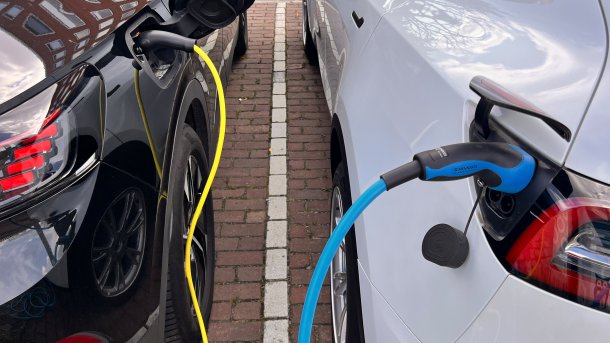 Zwei Elektroautos sind mit Ladekabel verbunden.