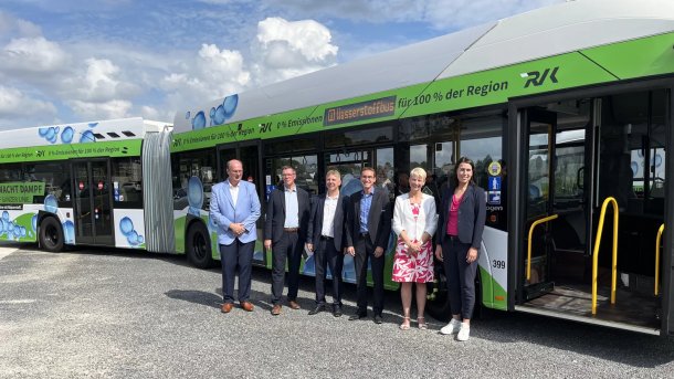 Menschen stehen vor einem Wasserstoff-Gelenomnibus
