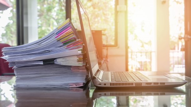 Papierstapel neben Laptop
