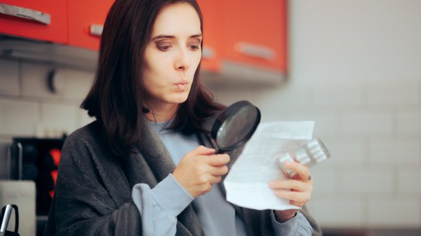 Woman reads a package insert with a magnifying glass