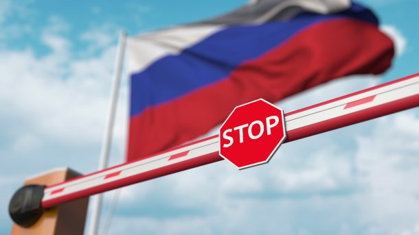 A barrier with a stop sign in front of a Russian flag