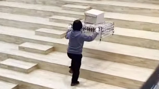 Frau bewegt mit Palletrone Cart eine Last Treppenstufen hinauf.