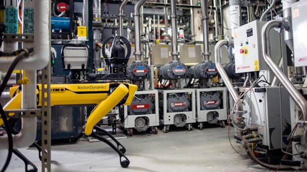 Robot dog Spot runs through an industrial complex.