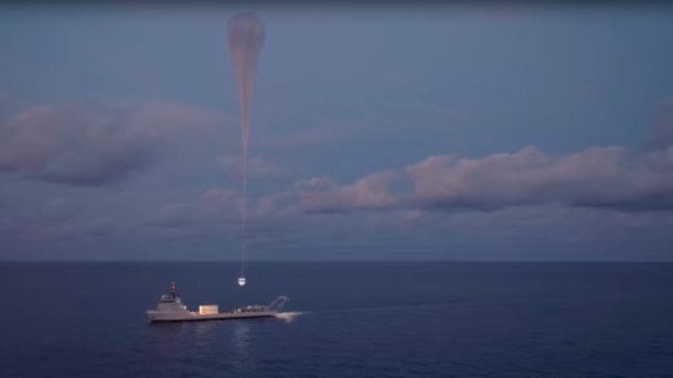 Space capsule launches with balloon from ship.