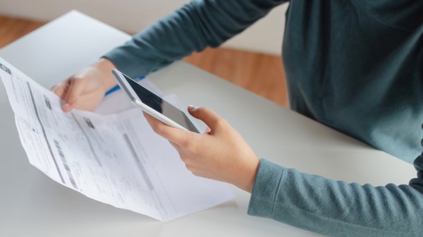 Person is sitting at their smartphone and possibly doing a tax return using an app