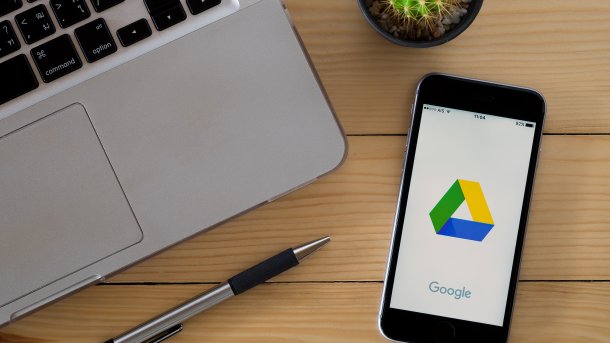 Google Drive auf einem Smartphone, links daneben ein Laptop und ein Stift