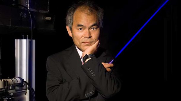 Shuji Nakamura, one of the three winners of the 2014 Nobel Prize in Physics, stands for a press photo with a blue laser model.