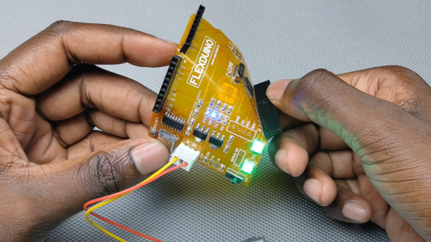 Hände biegen ein Arduino-Clone auf flexibler Platine