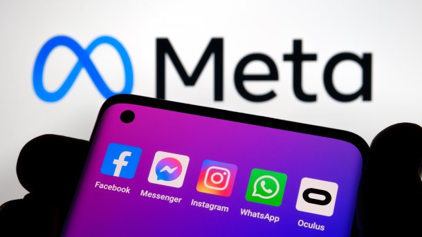 Smartphone mit den App-Icons für Facebook, Facebook-Messenger, Instragm, WhatsApp und Oculus, dahinter das Meta-Logo