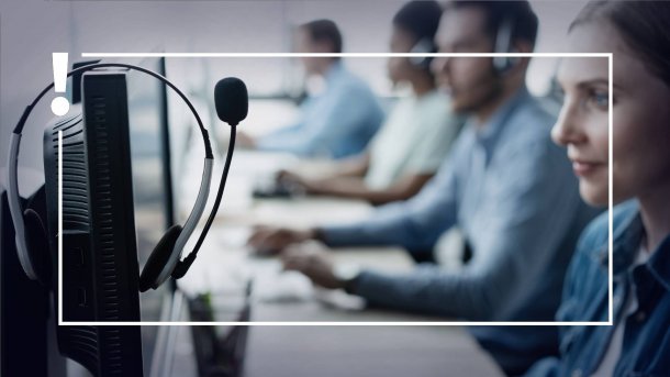 Menschen in einem Callcenter, die vor Bildschirmen mit Headsets sitzen