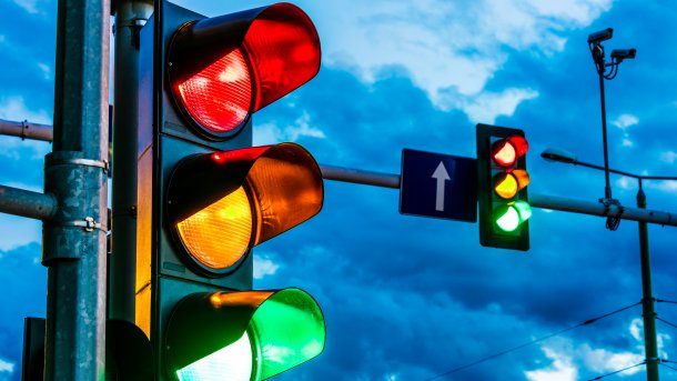 Two traffic lights against a cloudy evening sky.
