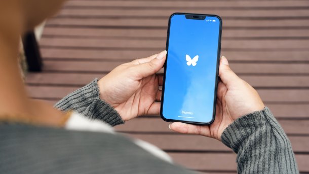 Person holding cell phone with Bluesky logo