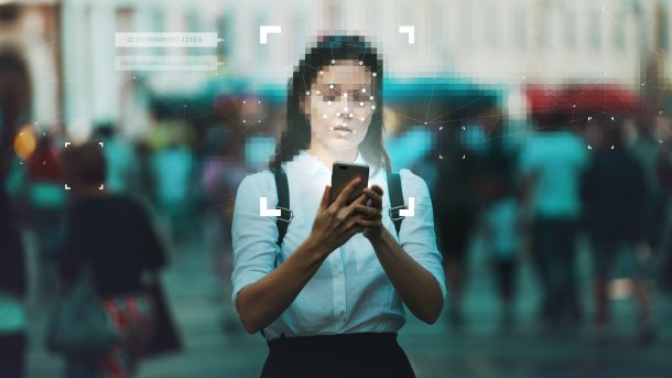 Young woman holds a smartphone in her hands, data flow and networks are graphically visualized around her.