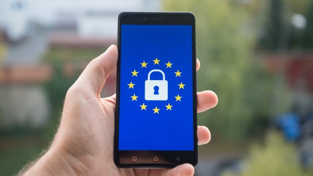 Mobiltelefon in Hand einer Person. Auf dem Handy ist ein Schloss mit EU-Sternchen zu sehen.