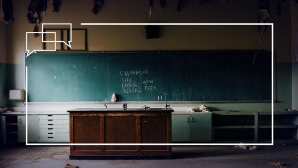 Verlassener Klassenraum. Auf der grünen Tafel steht mit Kreide geschrieben: 