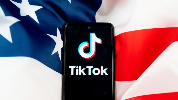 TikTok-Logo auf einem Smartphone, das auf einer US-Flagge liegt.