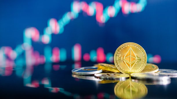 An Ether coin, with a rising stock market curve in the blurred background
