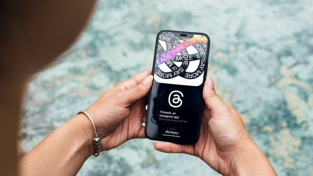 A smartphone in girls' hands, with the start page of Threads on it.