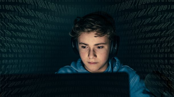 Kind schaut im Dunkeln auf einen Computer.