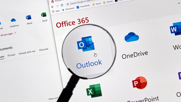 Microsoft Office Home" window. A magnifying glass enlarges the logo for Outlook. Next to it are the logos for OneDrive, Word, Excel and PowerPoint.