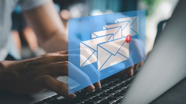 Mail symbols in front of a hand on a keyboard