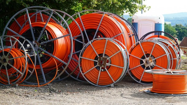 Large rolls of orange fiber optic cable for laying in the ground at a construction site in Beber, Lower Saxony.