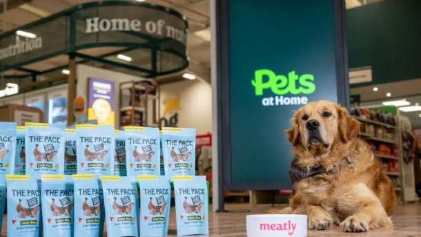 Tierfutterpackungen mit einem Hund daneben, der vor einer Futterschüssel sitzt, auf der "Meatly" steht
