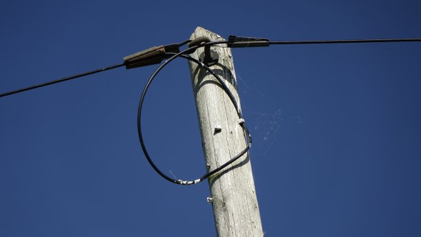 Top of a wooden utility pole with a stretched telephone line in Sehnde, Germany