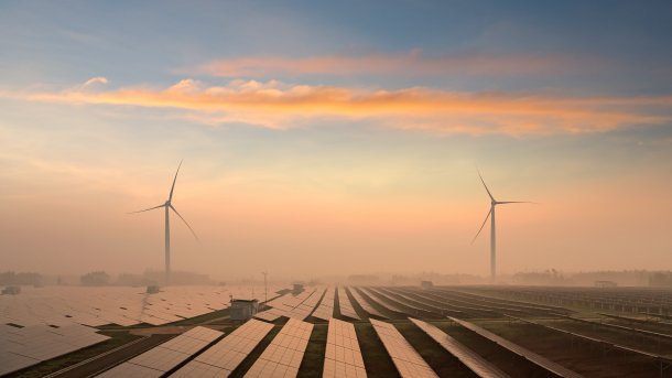 Windkraftanlagen hinter Solarpaneelen in der Landschaft
